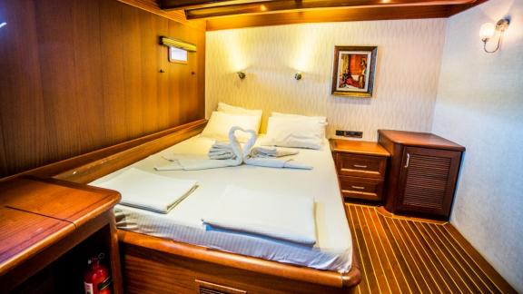 A cosy cabin with wooden furnishings and a decorated bed on the Gulet Freedom in Marmaris.