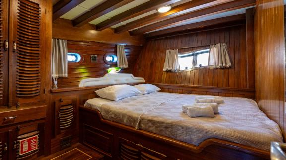 Gemütliche Kabine auf der Yacht Serenad mit Doppelbett, eleganter Holzausstattung und viel Stauraum.