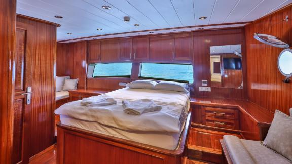 A luxurious cabin on the Gulet Kasapoglu 6 featuring a double bed, sofa, and large window with a sea view.