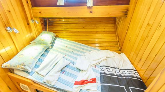 Compact single cabin with a cozy bed and wooden walls. Perfect for quiet nights at sea.