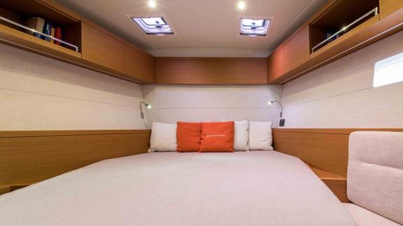 Spacious bedroom with red and white pillows on the luxury yacht Morea.