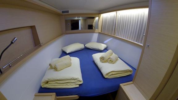 Well-lit double cabin in the Saelma Lagoon 450 with a window and soft towels on the bed.