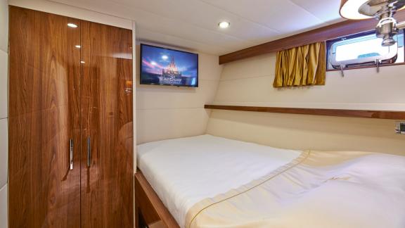 Modern guest cabin of the motor yacht Wide Liberty with a TV and comfortable double bed.