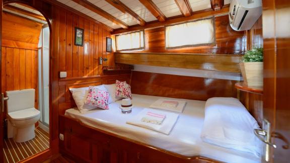 Comfortable bedroom with double bed, warm wood decor, and en-suite bathroom on the Gulet Sıla.