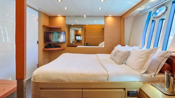 Ein modernes und helles Schlafzimmer auf der Yacht For Ever mit integriertem Fernseher.