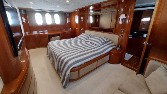 The luxurious bedroom of the yacht Cielo features a large bed, wooden furniture, and large windows.