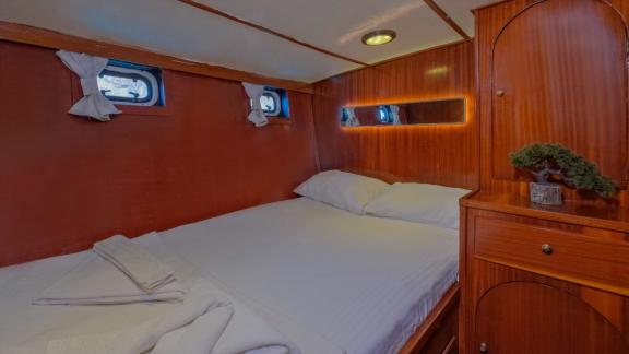 Cozy cabin on the trawler Grainne Mhaol with a double bed and wooden details.