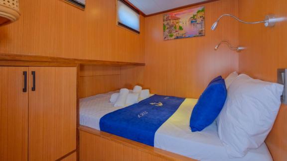 Compact single cabin on Gulet Anes with blue linens and nautical-themed decor.