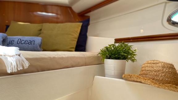 Schlafzimmer auf der Motoryacht Black Ball, dekoriert mit Accessoires wie Hut und Pflanze.