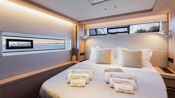 The master cabin of White Caps catamaran features modern decor and large windows for a bright and cozy atmosphere.