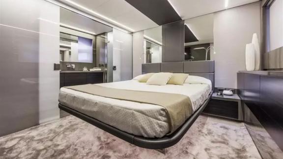 The modern master cabin of motor yacht Urus is furnished with a stylish bed and minimalist decor.