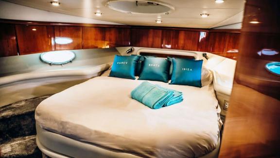 The master cabin of Fancy It yacht in Ibiza features a large round bed and portholes with harbor views.