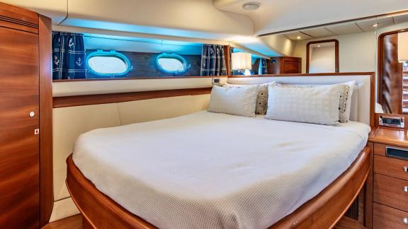 The cabin of Parodia II in Mallorca features a curved bed bedside lights and two curtained windows.