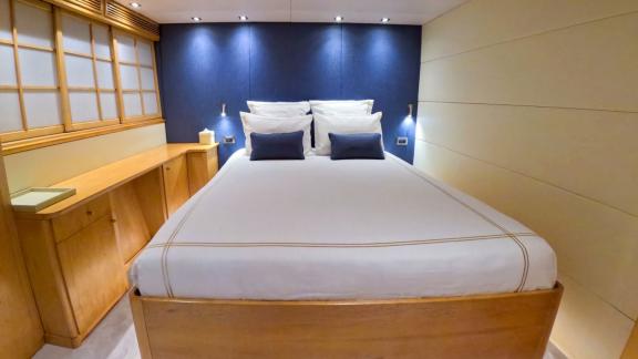 This double cabin on yacht Brooklyn features a deep blue headboard and natural wood elements, creating an elegant and in