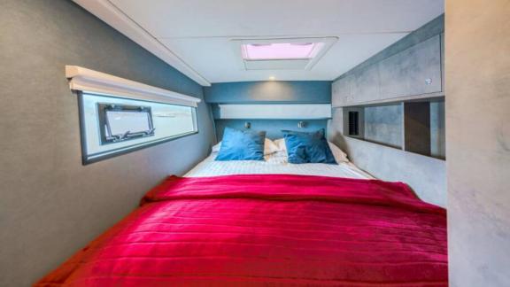 В каюте двуспальная кровать с синими подушками, красное покрывало, окно и люк в потолке.