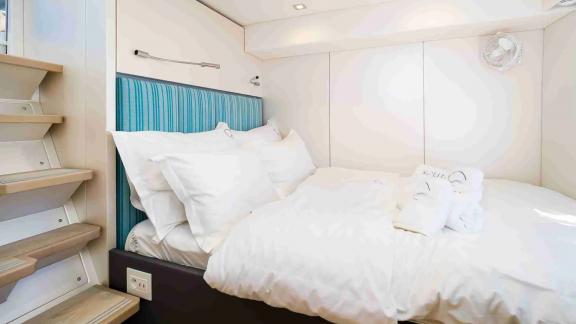 The guest cabin near the stairs on Sunreef 50 Solitaire features a double bed and minimalist, cozy styling.