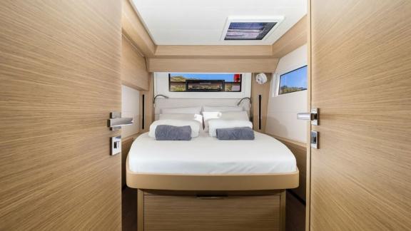 В просторной каюте — большая кровать, потолочный люк, боковые окна и настенное украшение.