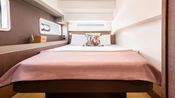 Elegant double bed in a bright sleeping cabin of the Bali 4.2 catamaran, featuring a window and decor.