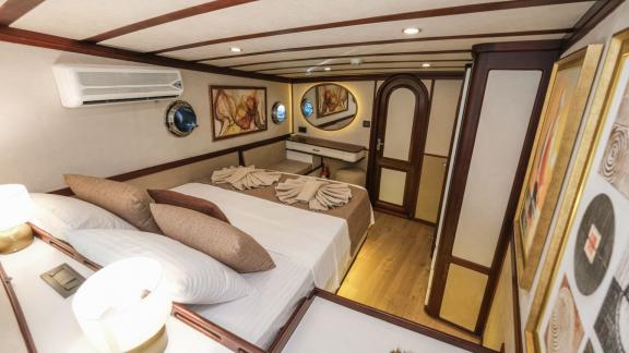 A comfortable double cabin on the Gulet Tarkan 5, equipped with a large bed, stylish wooden furniture and air conditioni