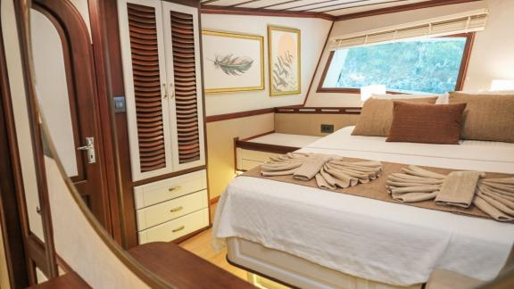 An elegant double cabin on the Gulet Tarkan 5 with a large bed, decorative cushions, air conditioning and tasteful wall 