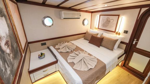 The cosy main cabin of the Gulet Tarkan 5 has a large bed, decorative murals and stylish wooden accents.