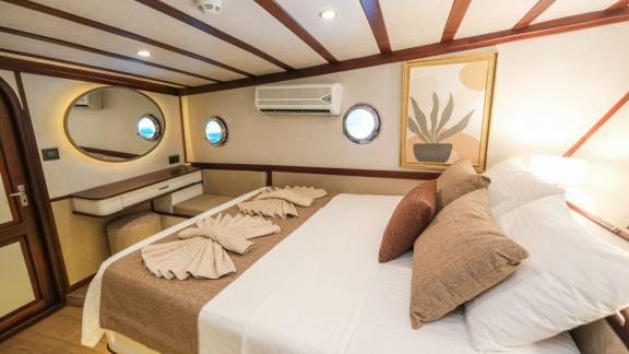 A luxurious sleeping cabin on the Gulet Tarkan 5 with high-quality bed linen, elegant wooden furniture and decorative el