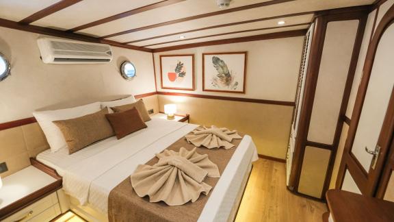 The decorative master cabin on the Gulet Tarkan 5 has a large bed, artistic murals and cosy lighting,