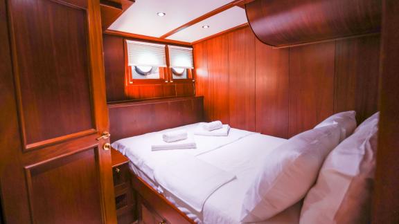 Gazella’s guest cabin features a double bed, wooden decor, and small windows.