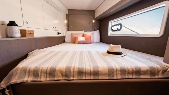 Modern double bed in a sleeping cabin of the Bali 4.2 catamaran, featuring a large window and stylish details.