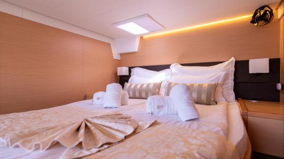 This Lagoon 560 Topaz cabin features modern design, soft lighting, and a comfortable double bed.