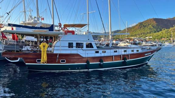 Gulet Ahmet Ertürk is anchored in a serene marina, featuring an eye-catching wooden hull.