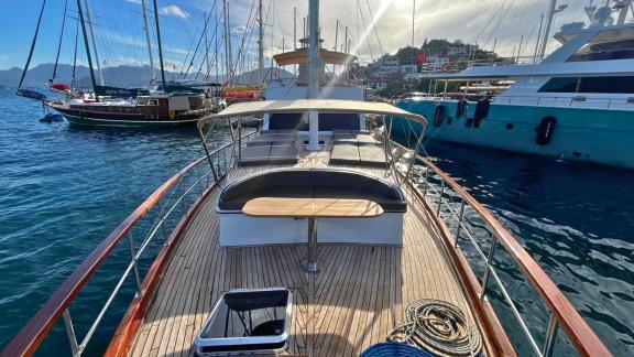 Gulet Ahmet Ertürk at the harbor, with sunbeds and a seating area on the front deck.