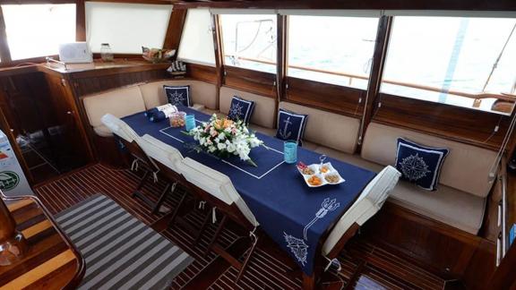 Stylish dining area inside Gulet Ali Aga 1, decorated with nautical pillows and a flower arrangement.