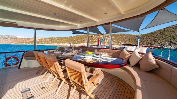 In Göcek gulet charter option Always Smile aft deck with dining table seating area and sea view visible.