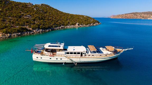 In Göcek gulet charter option Always Smile anchored in turquoise bay with sunbathing area on deck visible.