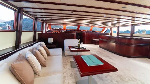 In Göcek gulet charter option Always Smile interior salon with seating area large windows and sea view visible.