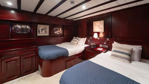 In Göcek gulet charter option Always Smile cabin with two single beds nightstand and lighting visible.