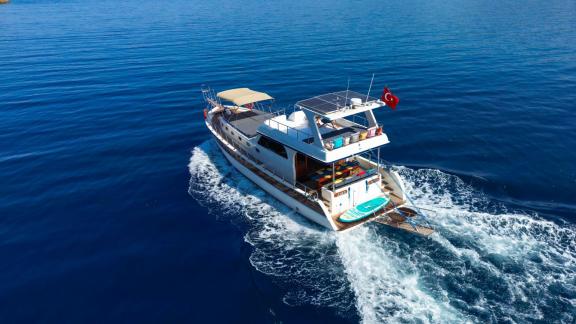 The Gulet Anes cruising with visible wake, featuring a sun deck and paddleboard, perfect for up to 6 people.