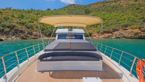 The spacious sun deck of Gulet Anes with comfortable loungers, perfect for relaxing in a tranquil bay.