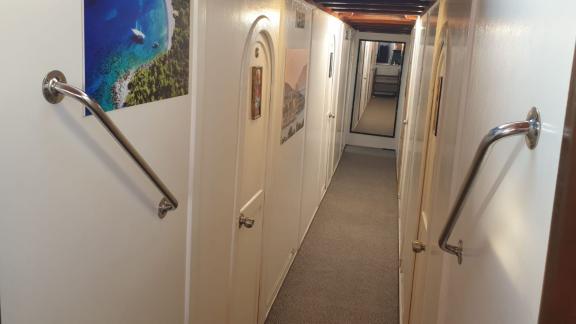 Bright and clean hallway with decorative pictures leading to the cabins of Gulet Arancia.