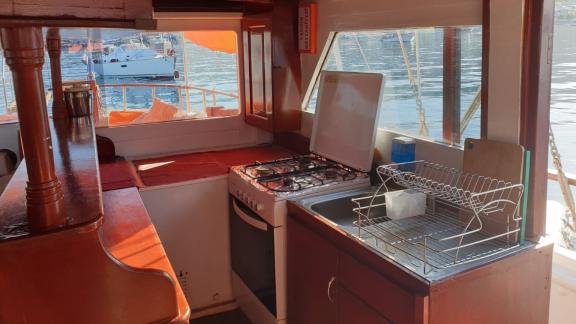 The well-equipped kitchen of Gulet Arancia features a gas stove, sink, and a view of the water.