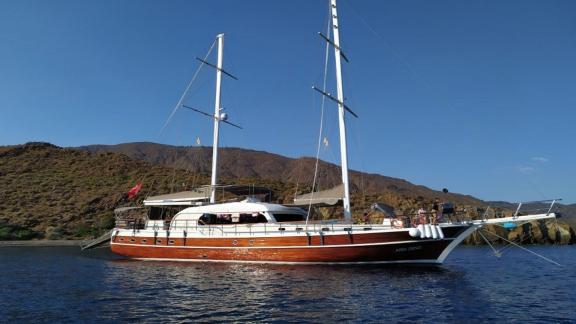 Die Gulet Arın Deniz liegt mit ihrem Holzrumpf friedlich vor Anker im offenen Meer.