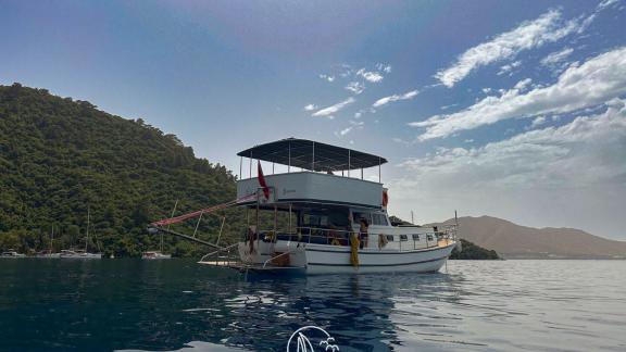 The aft deck of Gulet Ayken, anchored in a peaceful bay surrounded by nature.