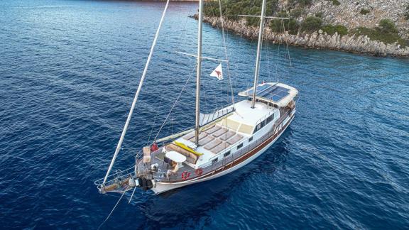 The Gulet Azura peacefully anchored in an idyllic bay in Göcek, surrounded by clear waters and green hills.