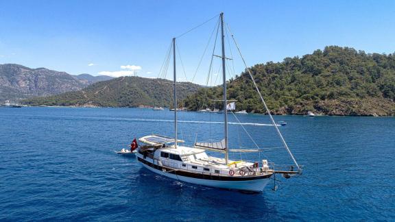 The Gulet Azura majestically sailing through the clear blue waters of Göcek, surrounded by green hills and islands.