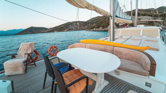 Gemütlicher Ess- und Loungebereich an Deck der Gulet Azura mit Blick auf die atemberaubende Küstenlandschaft von Göcek.