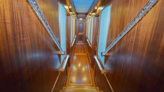 Well-kept wooden corridor on the gulet leading to the cabins, with atmospheric lighting and stylish details.