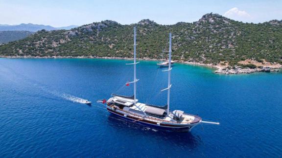 A magnificent gulet with six cabins is anchored in a quiet, picturesque bay in Marmaris, surrounded by emerald green wat