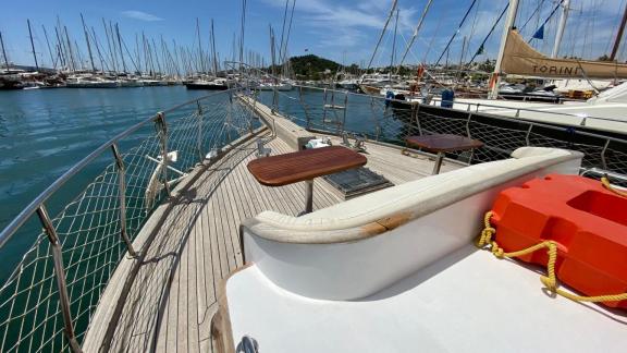 Палуба гулета Be Happy в гавани с зонами для сидения и многочисленными яхтами на заднем плане.