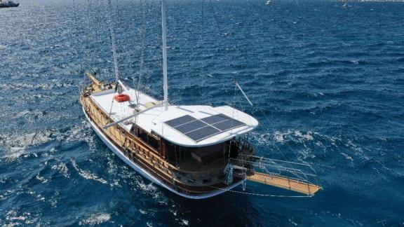 Гулет Be Happy плывет по открытому морю с солнечными панелями на крыше и синими водами вокруг.